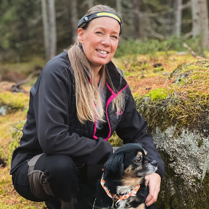 Femme avec son chien en forêt portant la lampe frontale Lumora pour une sortie en pleine nature